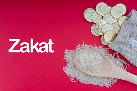 ZAKAT words with Coins and Rice on red background. Zakat concept. Zakat is a form of alm-giving as a religious obligation