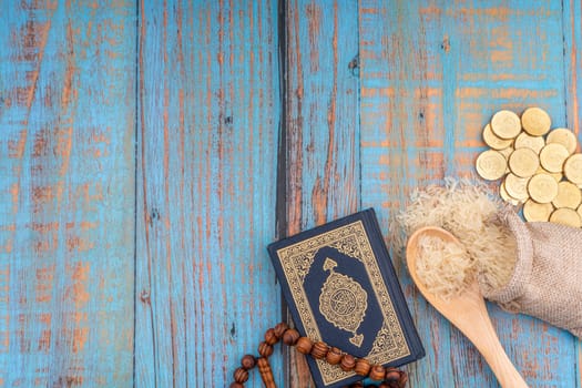 Holy Quran with arabic calligraphies translation meaning of Al-Quran, Coins, Rosary and Rice. Zakat concept. Zakat is a form of alm-giving as a religious obligation