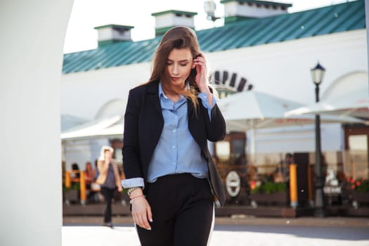 Young brunette woman in formal suit walking old town. Girl weared in blue shirt and black jacket.