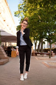 Fashionable women's look with black jacket, blue blouse and white sneakers. Fashion concept