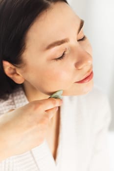 Young woman doing face Gua sha - chinese traditional massage