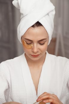 Pretty european girl applying golden collagen patches under her eyes. Woman facial treatment. Cosmetology, beauty and spa