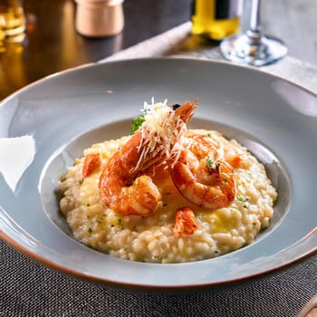 Risotto aux gambas features creamy Arborio rice topped with grilled prawns and garnished with colorful accents for an indulgent experience.