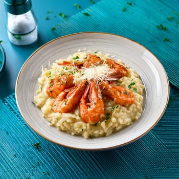 Risotto aux gambas features creamy Arborio rice topped with grilled prawns and garnished with colorful accents for an indulgent experience.