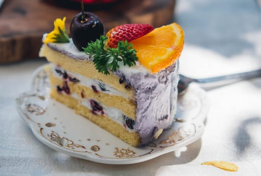 Close up Slice birthday fruit cake in plate violet delicious cream in layer
