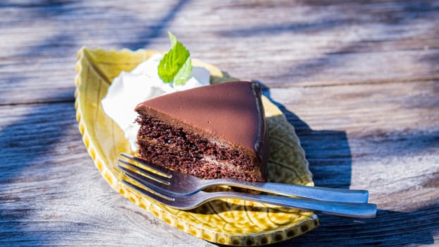 chocolate fudge cake serve with cream on vintage wooden table.