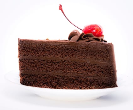 Chocolate cake with topping cherry in ceramic plate. Delicious cuisine dessert over white background