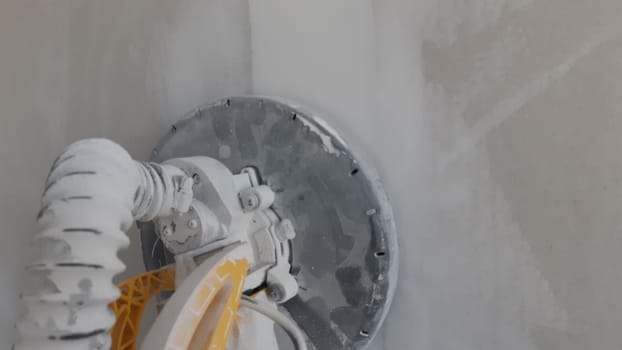 Plasterboard circular sander during DIY renovation works in residential room in house or apartment. Do it yourself.