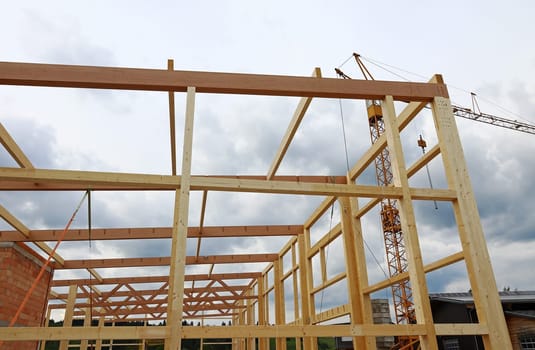 Wooden beams and crane at a construction site. The construction of a large wooden house.