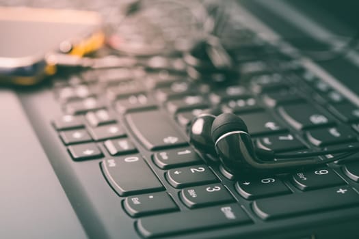 Black earphones with smart phone on keyboard in black