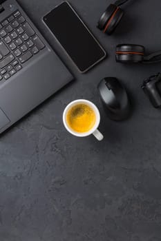 Working place and office desk with coffee, laptop, headset and smarthpone. Flatlay in black tone.