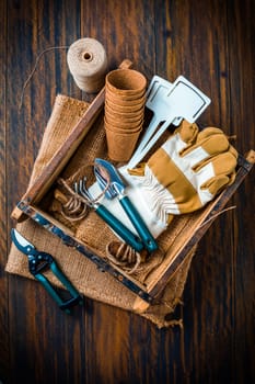 Gardening tools and equipment in wooden box on wooden background
