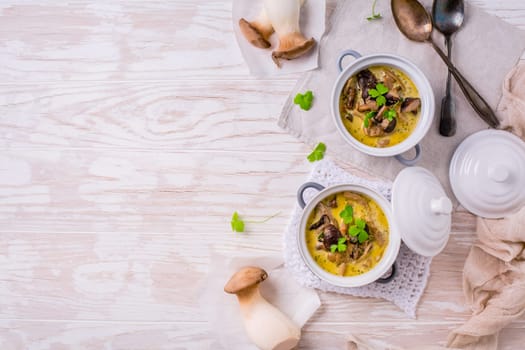 Delicious mushroom soup with herbs in serving pot on wooden table