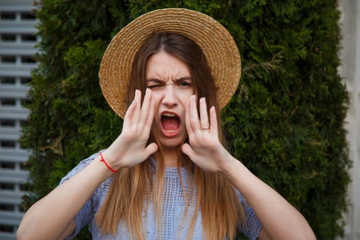 Beautiful young woman in summer hat shouting.