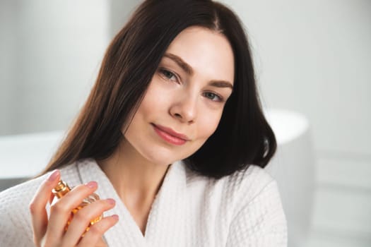Young brunette woman portrait with perfume jar in hand.