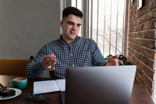 Man has conference call using laptop at home, coffee cup. Blurred background. High quality photo