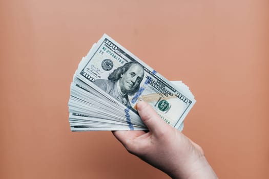 Bundle of dollars in hand on beige background. High quality photo
