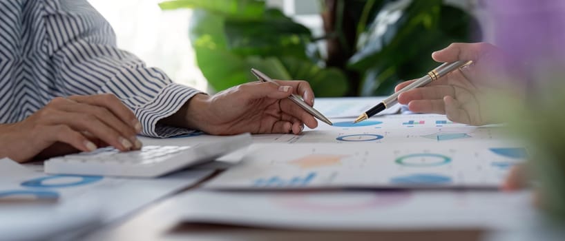 Finance experts collaborate on financial data and calculations, emphasizing teamwork and analytical skills in a bright office setting.