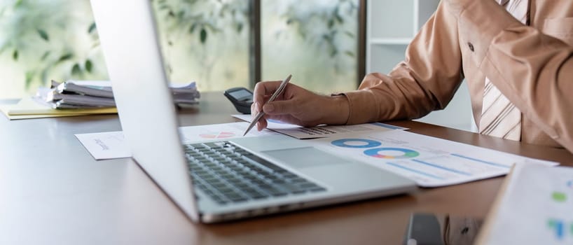 A business professional analyzes financial reports on a laptop, demonstrating strategic financial management and analysis.