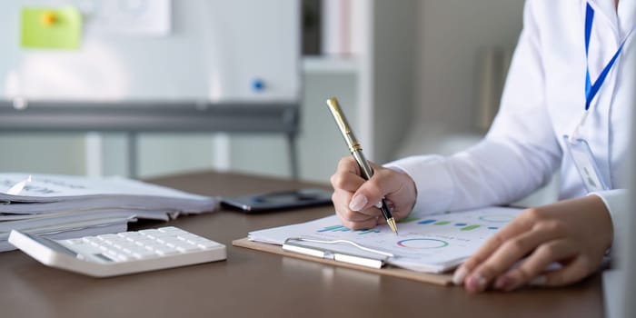 An accountant meticulously analyzes financial reports using a pen and calculator, ensuring accurate budgeting and financial management.