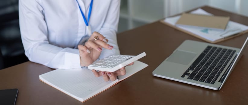 A financial expert calculates figures with a calculator, emphasizing accuracy in financial management and analysis.
