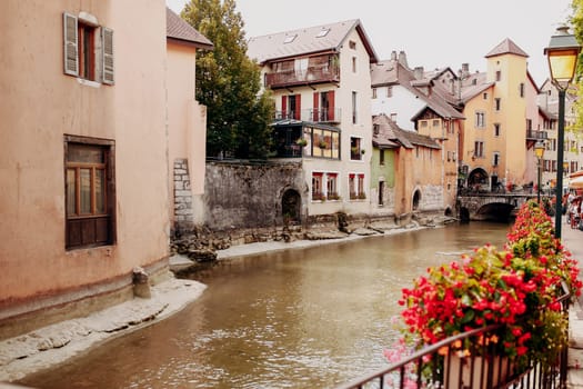 Annecy city water channel with red flowers and old buildings. High quality photo