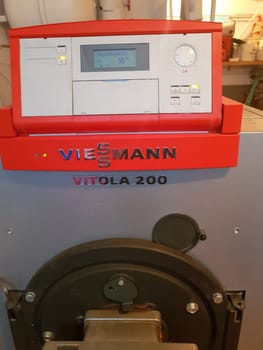 HEILIGENHAUS, NRW, GERMANY - FEBRUARY 15, 2019:.A domestic boiler room with a new modern oil fuel boiler, and a hot water supply and piping.
