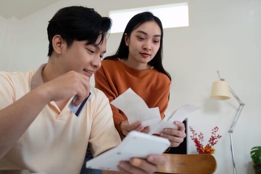 A couple manages their bills and financial information using a credit card, demonstrating teamwork and effective financial planning at home.