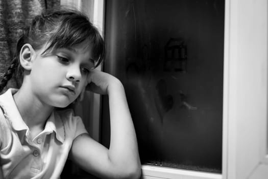 Girl draws figures of little men on a fogged window
