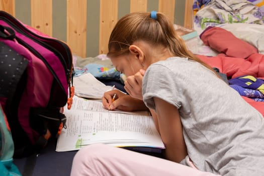 Schoolgirl does her homework on a spread out couch piled high with things