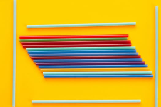 A bunch of multicolored cocktail tubes lies on a yellow background