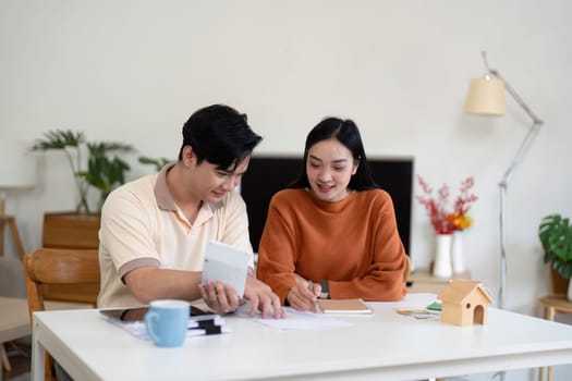 A couple sits together at a table, reviewing financial documents and discussing their budgeting strategies.