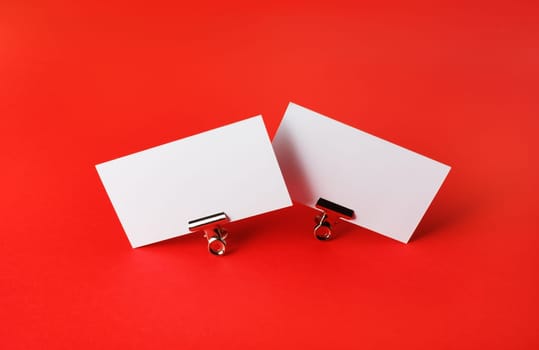 Photo of two blank business cards on red paper background. Branding ID template.