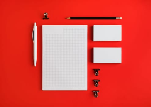 Photo of blank stationery set on red paper background. Corporate identity mock up for placing your design. Top view. Flat lay.