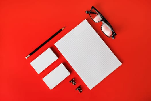 Blank stationery template on red paper background. Mock-up for branding identity. For design presentations and portfolios. Top view. Flat lay.