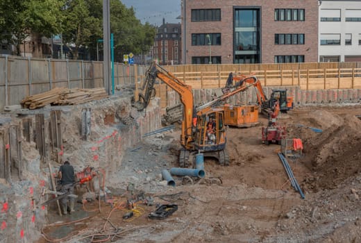 Worker in the foundation trench with construction machinery on the construction site