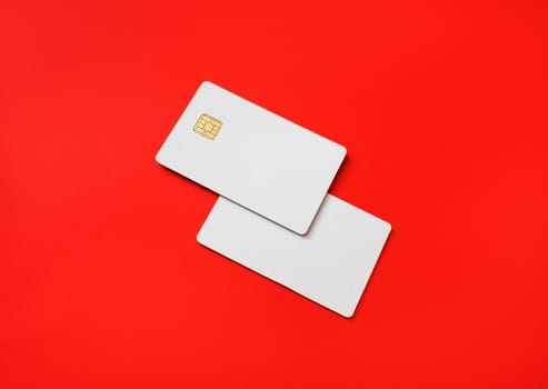 Photo of two blank credit cards on red paper background. White bank cards.