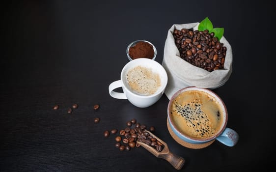 Making coffee still life. Coffee cups, roasted coffee beans in canvas bag and ground powder on black wood table background.
