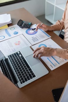 A finance expert reviews charts and data on a laptop, focusing on calculations for informed business decisions.