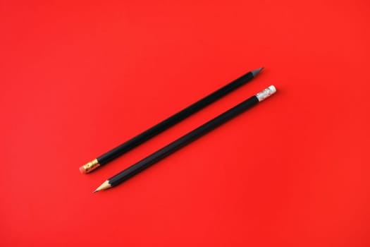 Black pencils with copy space on red paper background. Space for text.