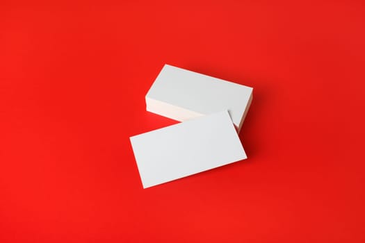 Photo of blank business cards on red paper background. Template for ID.