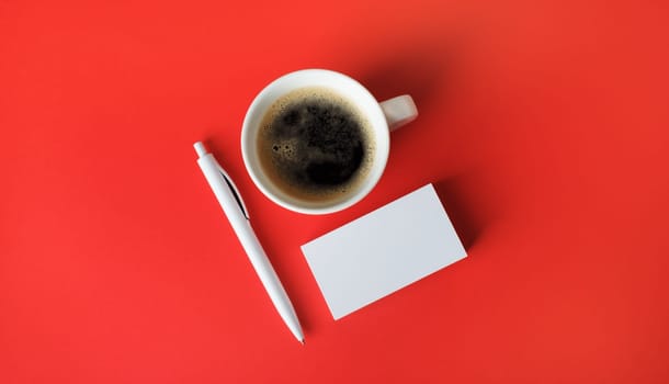 Blank business cards, coffee cup and pen on red paper background. Top view. Flat lay.