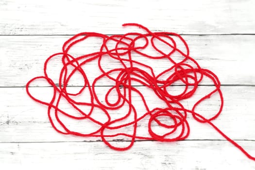 tangled red wool on white wooden table