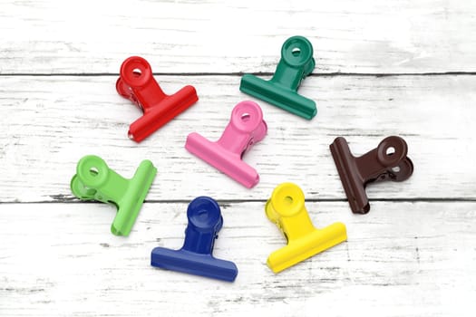 Colorful paper clips on white grunge wooden table