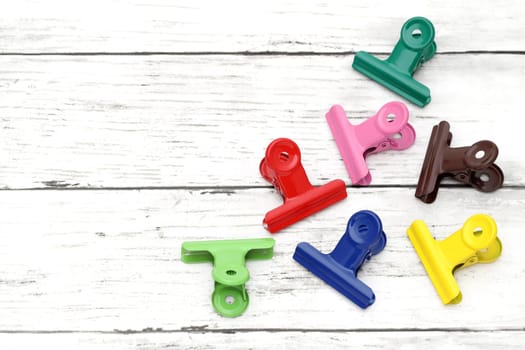 Colorful paper clips on white grunge wooden table