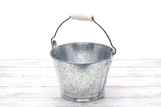 Empty metal bucket on white grunge wooden table