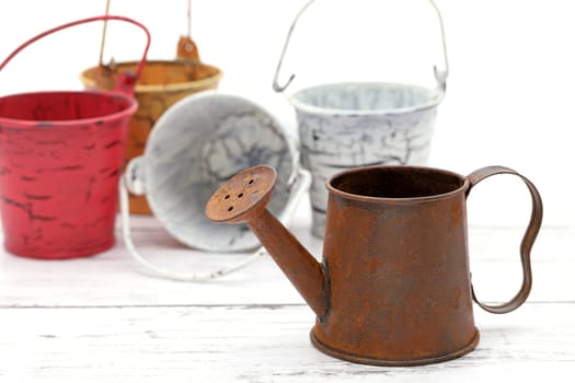rusted old miniature watering can with bucket on wooden white table