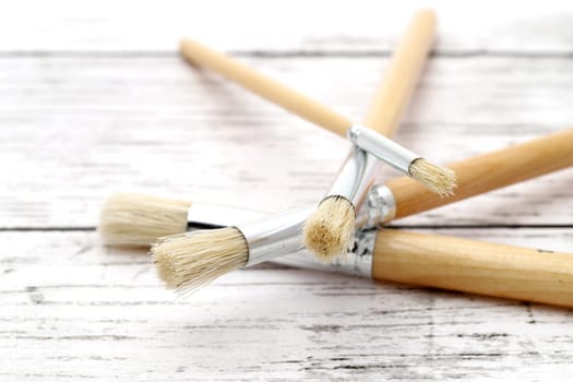 Paint brushes on white grunge wooden table