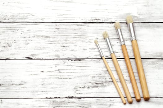 Paint brushes on white grunge wooden table