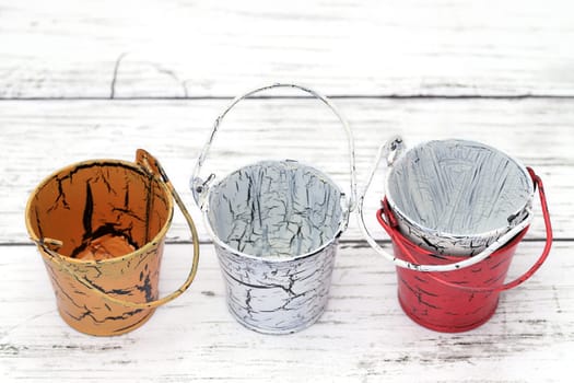 Empty miniature metal bucket on white wooden table